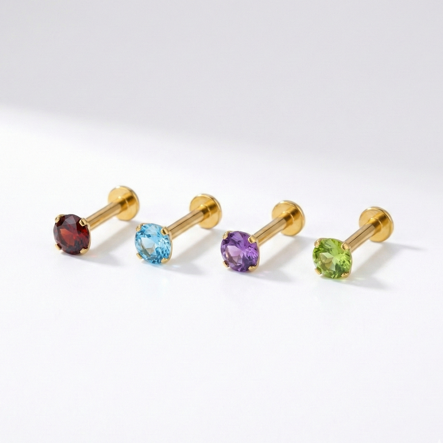 Collection of Minimal 14K Gold Natural Stone Flatback Studs in garnet, blue topaz, amethyst, and peridot, perfect for mix-and-match cartilage or nose piercings.