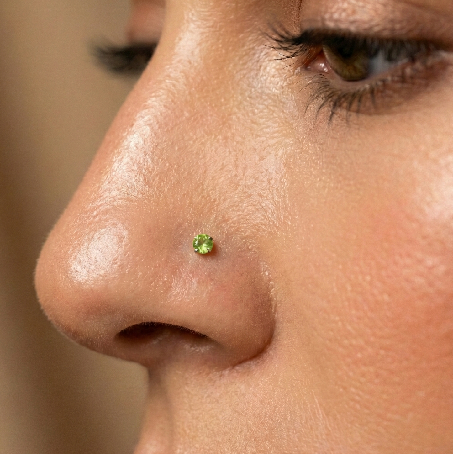 9K Gold L-Bend Nose Stud with vibrant green peridot stone worn on nose, showcasing elegant fit and natural gemstone sparkle.