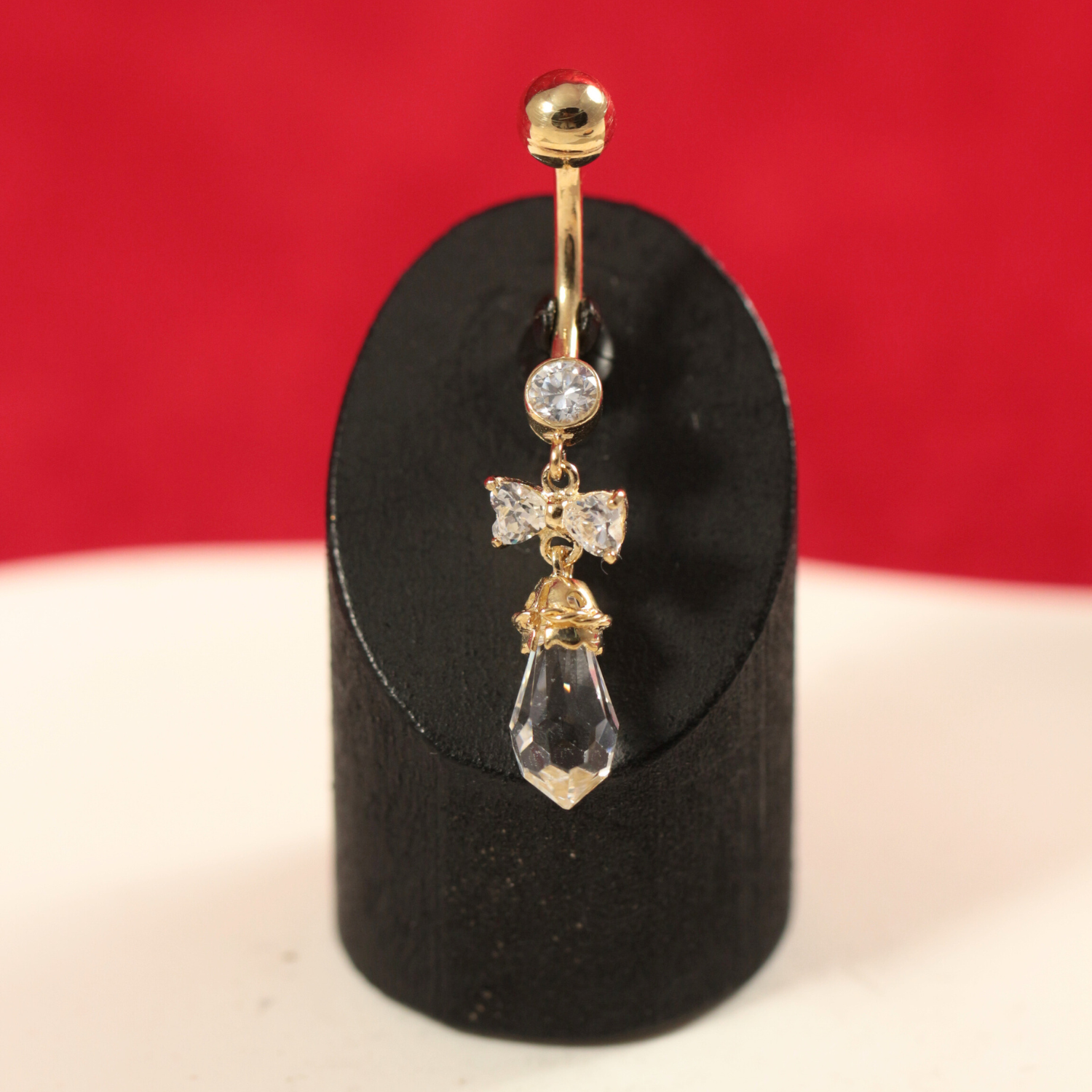 14K Gold Jewelled Dangling Bow Belly Ring displayed on stand