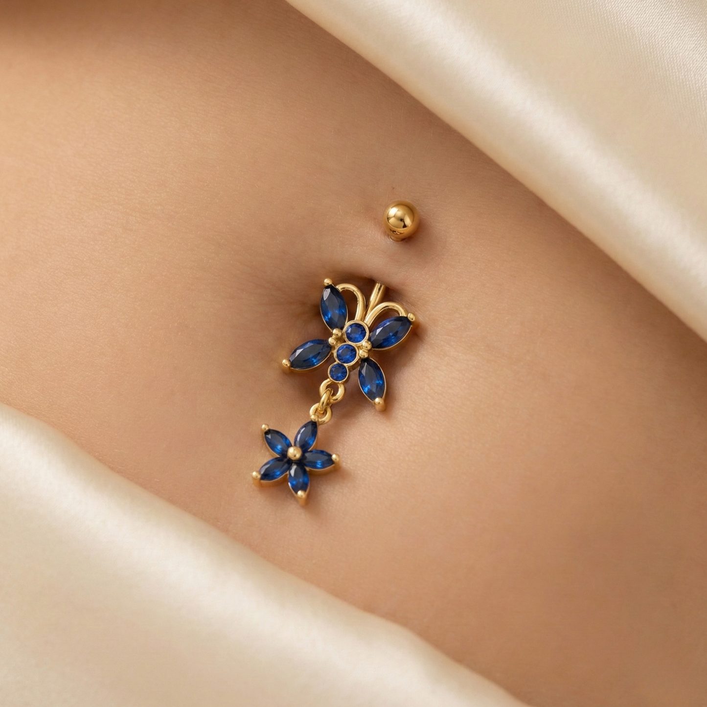 14K Gold Blue Studded Butterfly Belly Ring worn on navel, showcasing its sparkling blue stones and dangling butterfly charm for a stylish look.