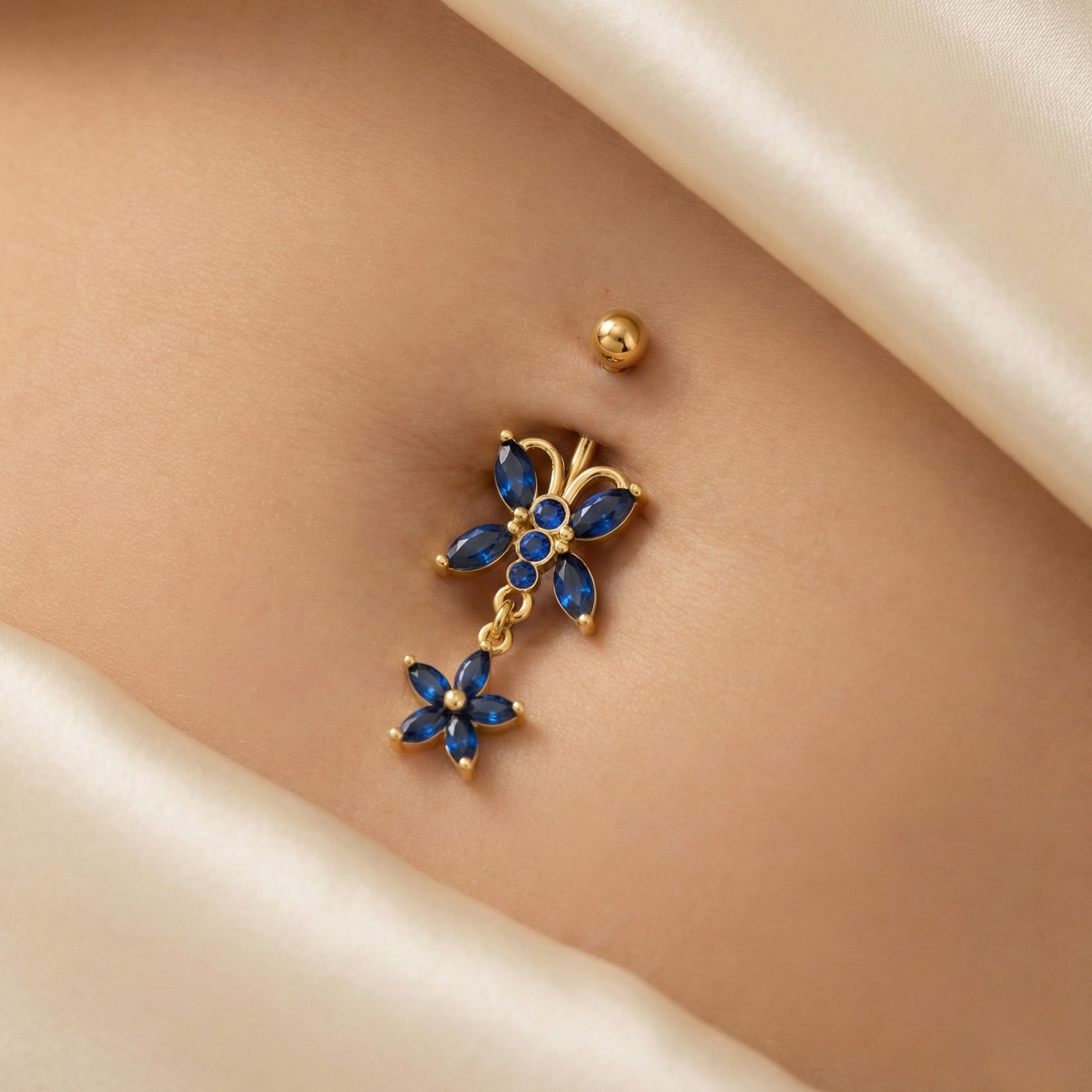 14K Gold Blue Studded Butterfly Belly Ring worn on navel, showcasing its sparkling blue stones and dangling butterfly charm for a stylish look.