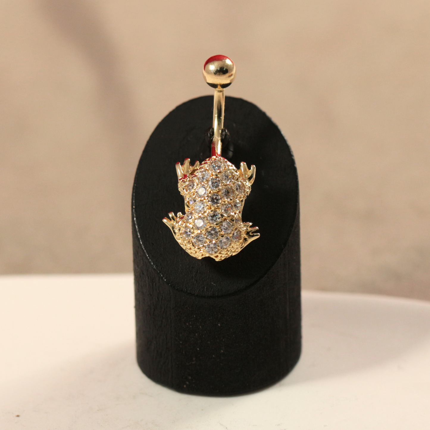 Charming 14ct Gold Jewelled Frog Belly Button Ring displayed on a black stand, highlighting its intricate gem-studded frog design and gold finish.