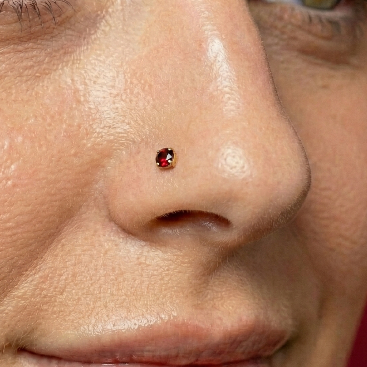 Minimal 14K Gold Garnet Natural Stone L-Bend Nose Stud worn on nose, showcasing its elegant red gemstone and subtle gold setting for daily wear.