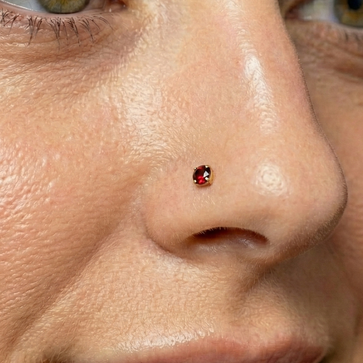 14K Gold Garnet Natural Stone Nose Screw worn on nose, showcasing rich red sparkle and secure fit for elegant everyday jewelry style.