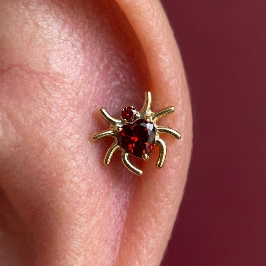 Gold G23 Titanium Spider Heart Threadless Accessory Top worn on ear cartilage, featuring red heart-shaped cubic zirconia for a bold look.