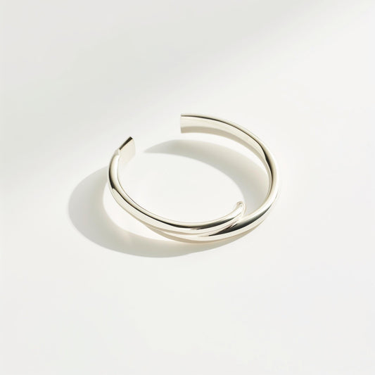 Minimalist silver cuff bracelet with a twisted open design, perfect for modern fashion accessories. Example product for elegant wristwear.