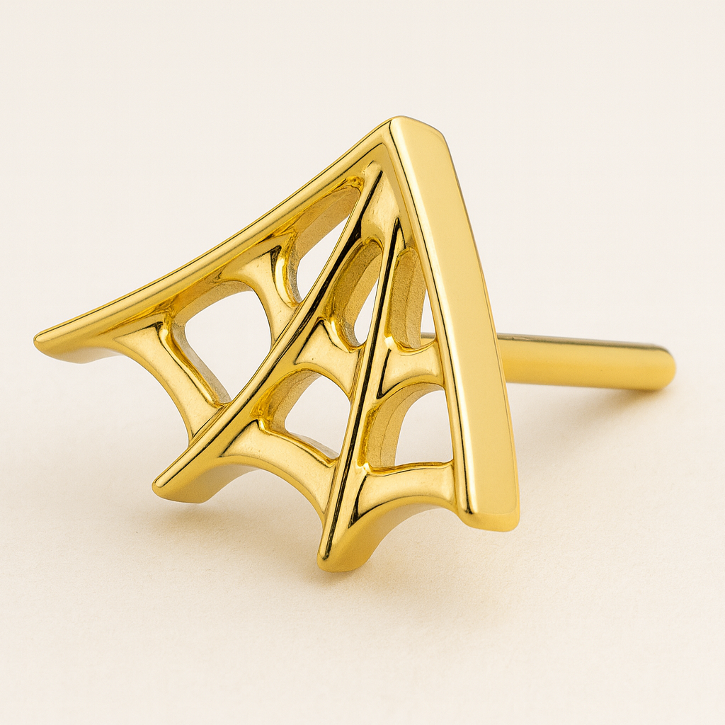 Close-up of gold spider web flatback stud in G23 titanium. Features a polished finish and intricate web design for body jewelry lovers.